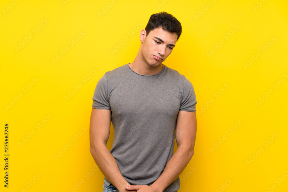 Handsome man over isolated yellow wall with sad and depressed expression Handsome man over isolated yellow wall with sad and depressed expression