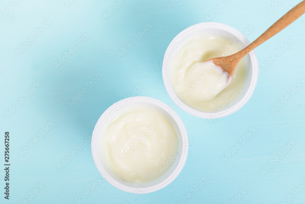 Plastic cup of yoghurt with wooden spoon on pastel background, healthy eating, top view Plastic cup of yoghurt with wooden spoon on pastel background, healthy eating, top view