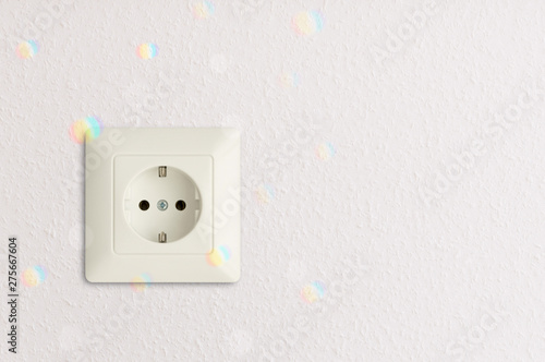 electrical power socket with reflections of spectral prism rainbow colours on white wall