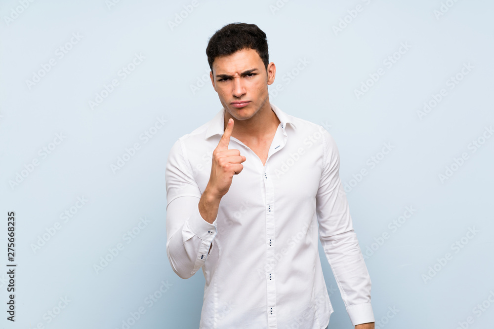 Handsome man over blue wall frustrated and pointing to the front Handsome man over blue wall frustrated and pointing to the front
