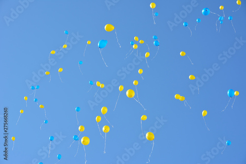 Many blue and yellow balloons flying high in the sky. Blue sky with lots balloons.