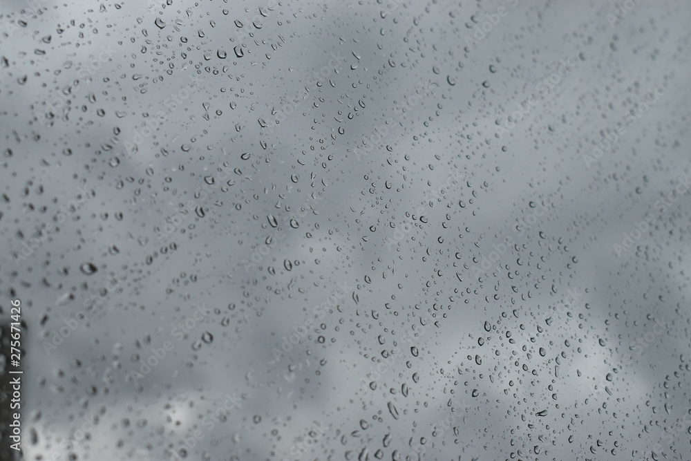 Rain water drops on the window glass, blurred background of clouds on the sky Rain water drops on the window glass, blurred background of clouds on the sky