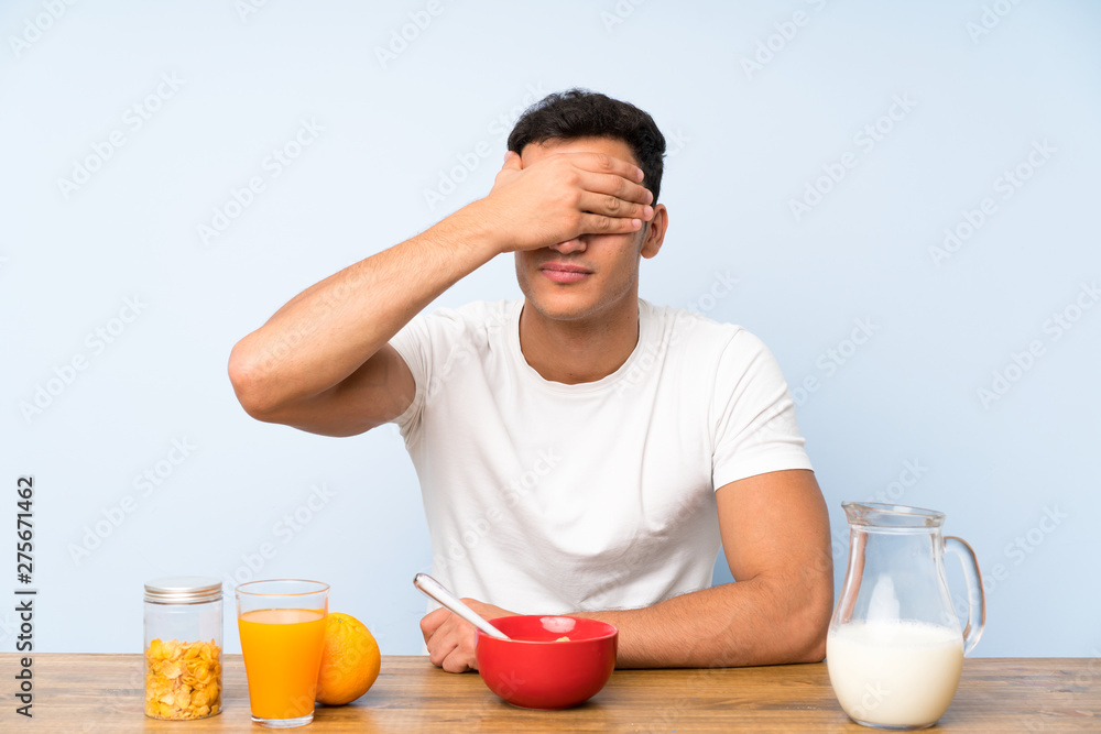 Handsome man in having breakfast covering eyes by hands Handsome man in having breakfast covering eyes by hands