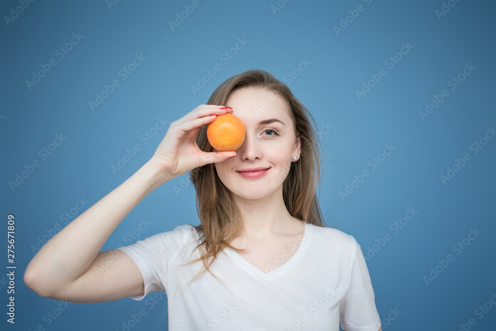 Young beautiful girl model with orange, blue background, holding orange, Young beautiful girl model with orange, blue background, holding orange,
