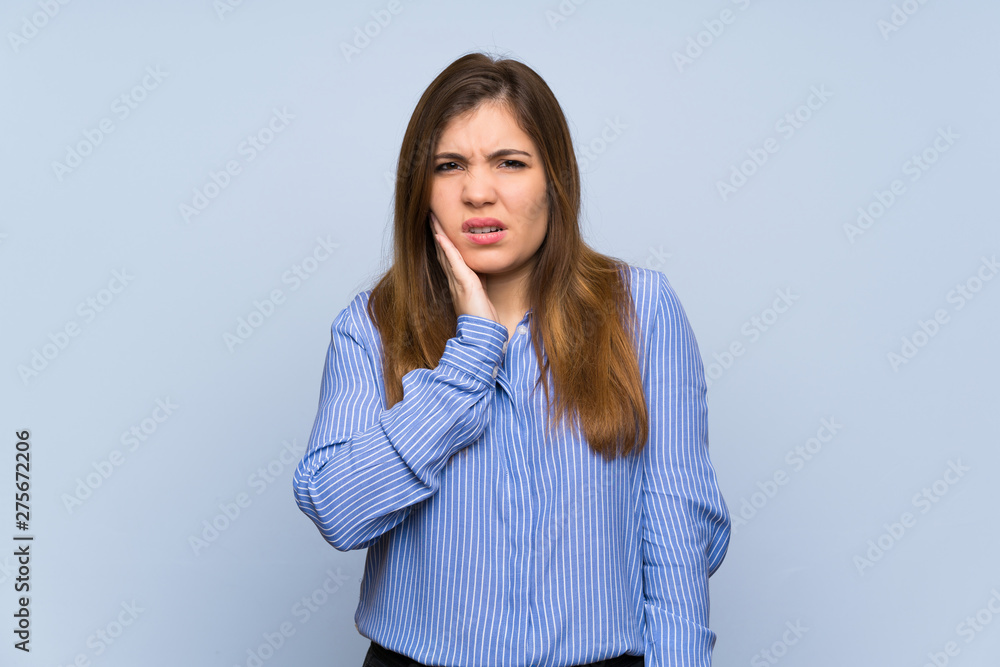 Young girl over isolated blue wall with toothache Young girl over isolated blue wall with toothache
