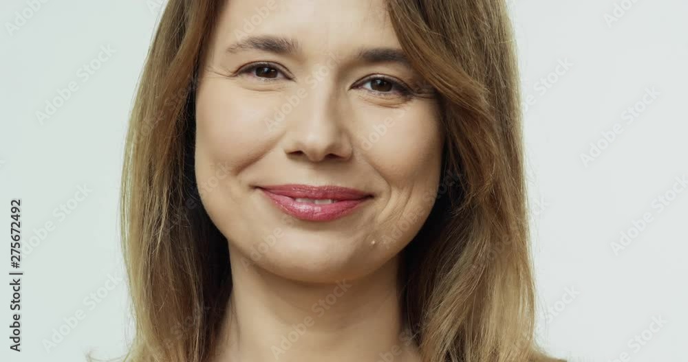Portrait of the beautiful middle aged Caucasian woman with smooth healthy skin smiling joyfully t the camera. Close up. Portrait of the beautiful middle aged Caucasian woman with smooth healthy skin smiling joyfully t the camera. Close up.