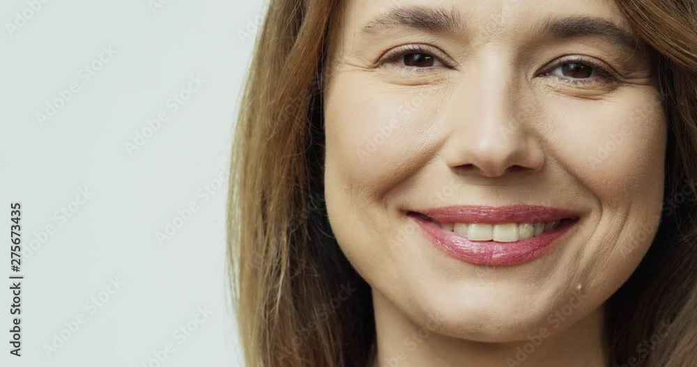 Portrait of the happy Caucasian attractive middle aged woman looking straight to the camera and smiling cheerfully on the white background. Close up. Portrait of the happy Caucasian attractive middle aged woman looking straight to the camera and smiling cheerfully on the white background. Close up.
