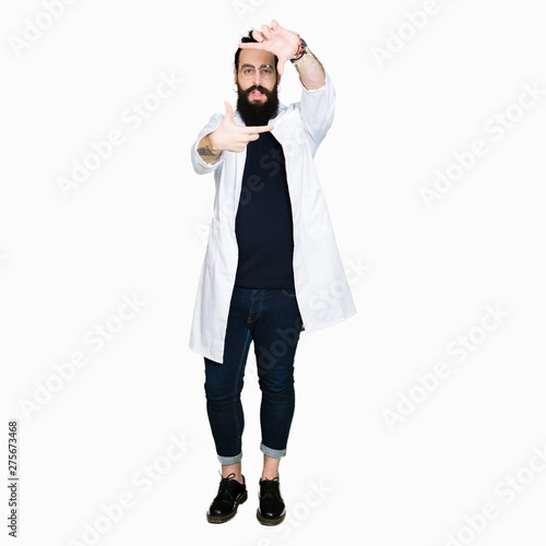 Doctor therapist man with long hair and bear wearing white coat smiling making frame with hands and fingers with happy face. Creativity and photography concept.