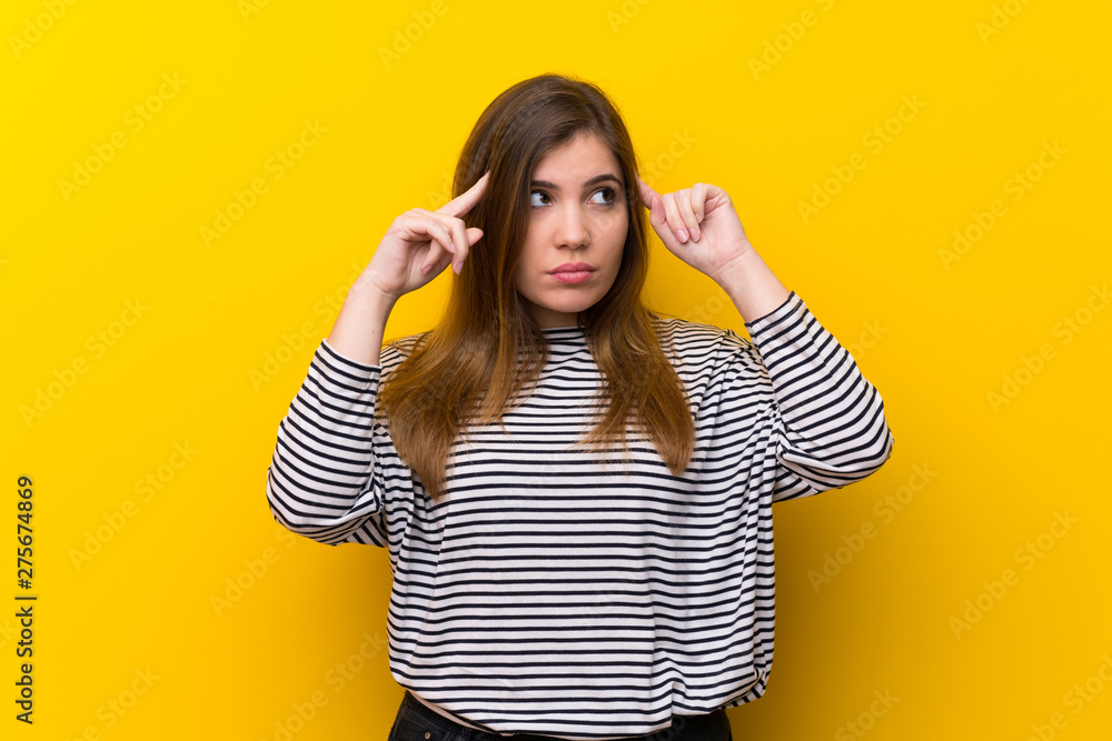 Young girl over yellow wall having doubts and thinking Young girl over yellow wall having doubts and thinking