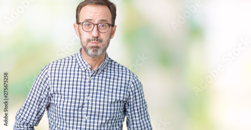 Handsome middle age elegant senior man wearing glasses over isolated background puffing cheeks with funny face. Mouth inflated with air, crazy expression.