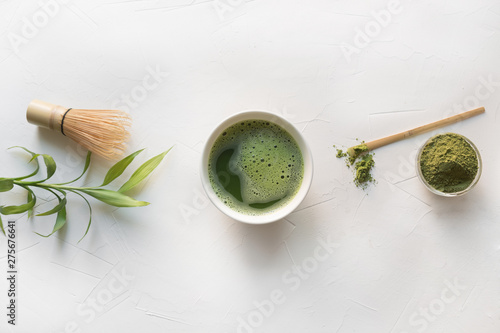 Ceremony green matcha tea and bamboo whisk on white concrete table. Top view.