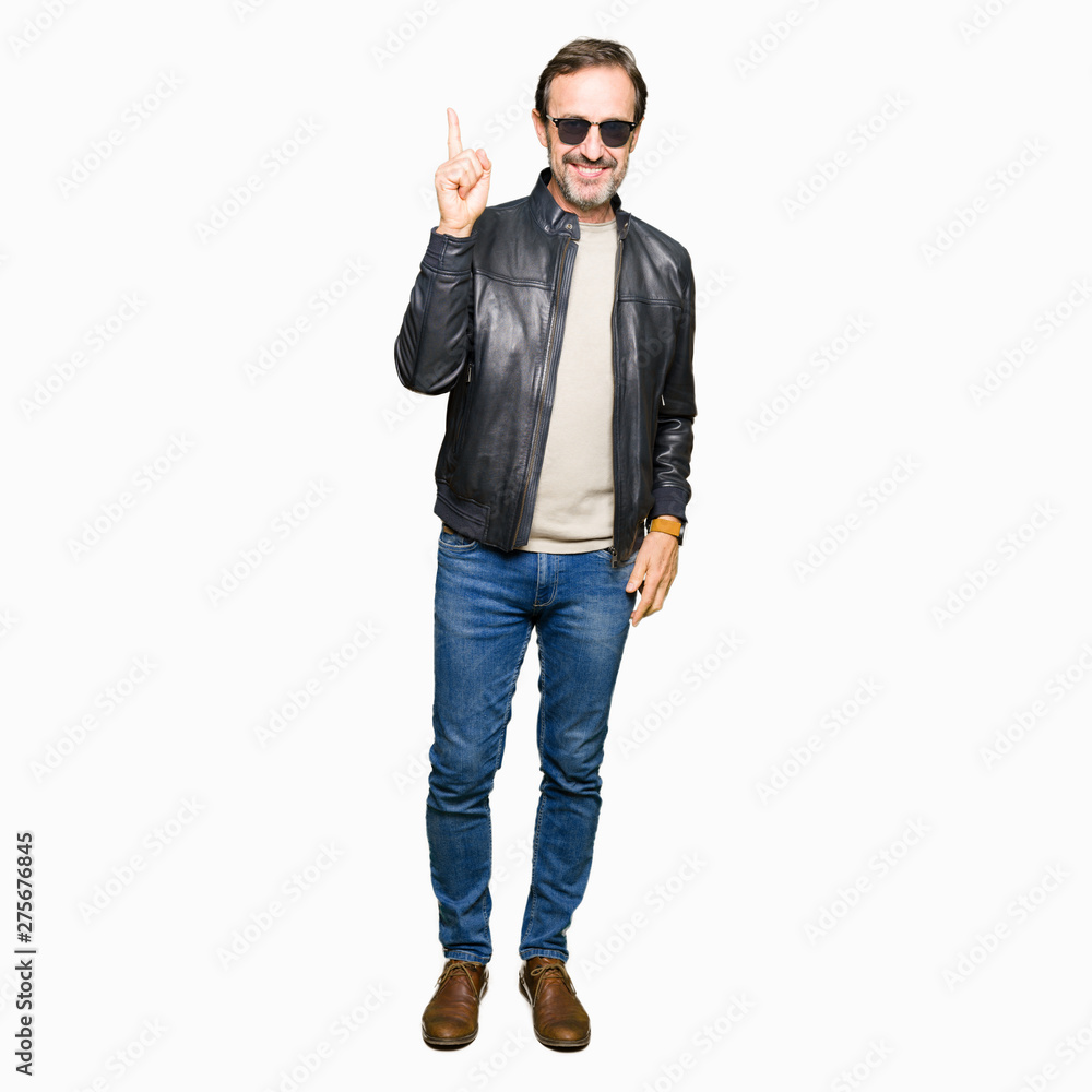 Middle age handsome man wearing sunglasses and black leather jacket pointing finger up with successful idea. Exited and happy. Number one. Middle age handsome man wearing sunglasses and black leather jacket pointing finger up with successful idea. Exited and happy. Number one.