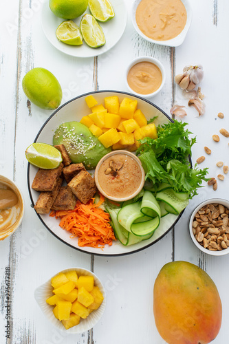 Healthy summer fresh salad with mango  avocado  lime and tofu with sweet peanut butter dressing on white wooden table