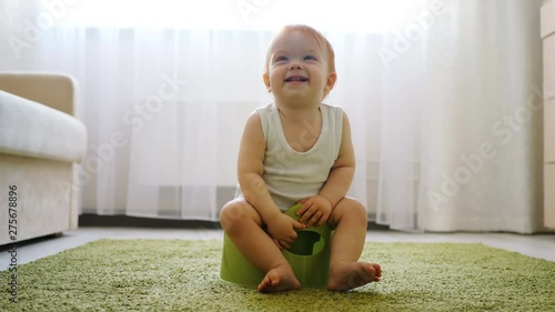 Redhead baby girl sitting on chamberpot in bright room close-up