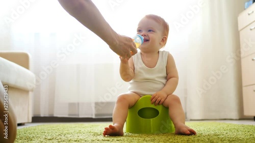Redhead baby girl sitting on chamberpot in bright room close-up