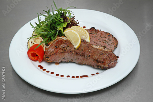 Steak beef with lemon, fried zucchini and pepper. Isolated on gray background