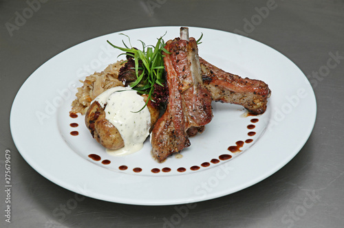 Grilled juicy barbecue pork ribs, stuffed potatoes, sauceon a white plate on gray background