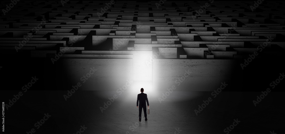 Businessman getting ready to enter the dark labyrinth with illuminated door
