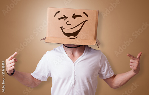 Young boy standing and gesturing with a cardboard box on his head 