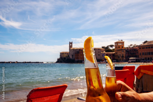 Canvas-taulu Two bottles of fresh beer with lemon wedges raised for a toast on a sandy beach