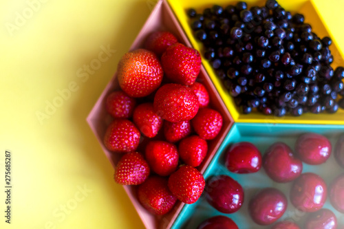 Cherries  strawberries  blue berries on yellow background. Colorful concept. Natural organic vegan healthy fresh food.