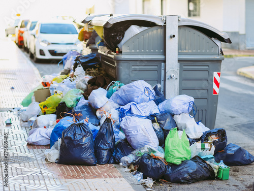 Piles of plastic garbage bags stacked next to the container