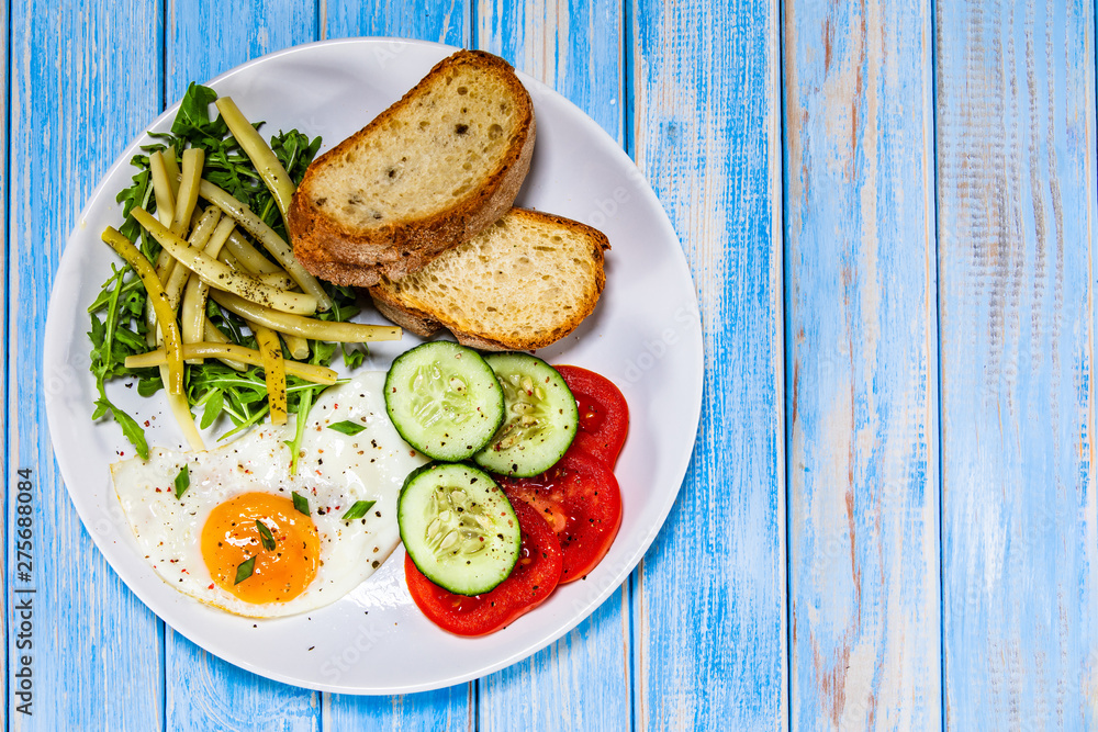Breakfast - fried egg, toasts and vegetable salad Breakfast - fried egg, toasts and vegetable salad
