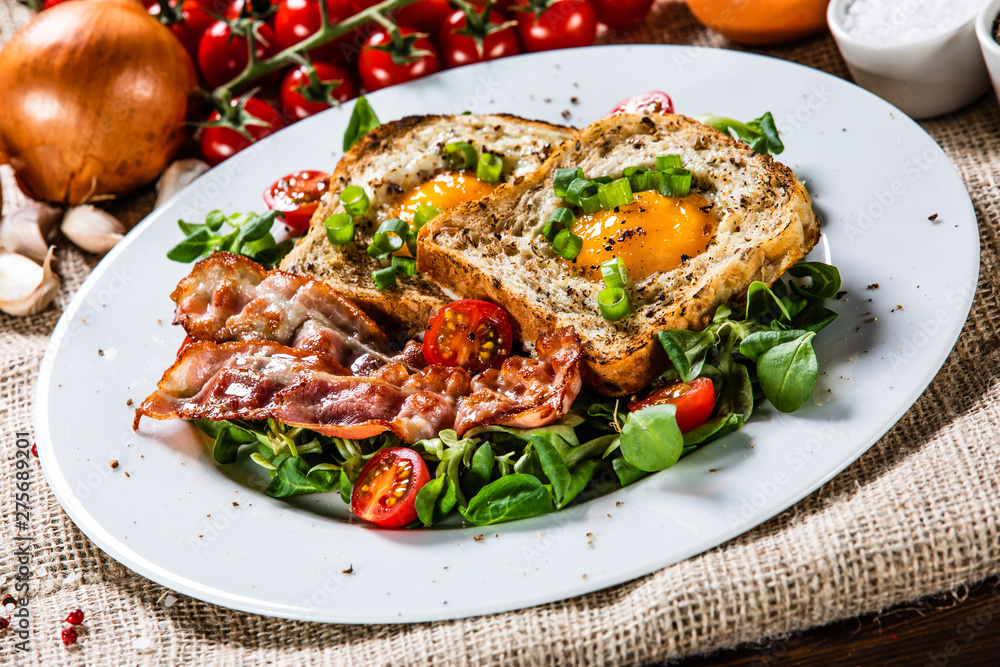 Breakfast - toasted bread with fried egg, bacon and vegetables Breakfast - toasted bread with fried egg, bacon and vegetables