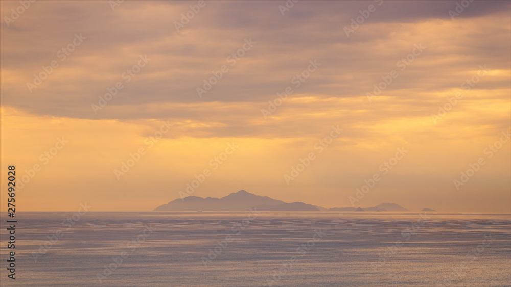 Silhouette Island in the sea with storm clouds and golden light