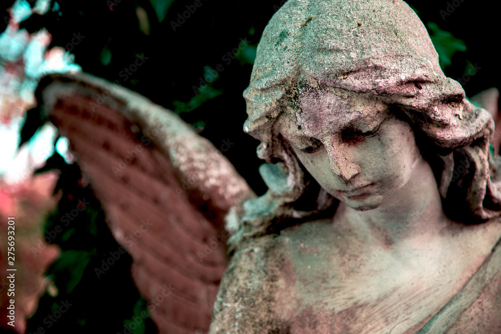 A fragment of ancient sculpture angel in a golden glow in the old cemetery. Symbol of love, invisible forces, purity, enlightenment, ministry. Chariot. Retro vintage style.
