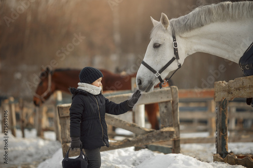 Vászonkép Teenage girl standing near white horse in a paddock