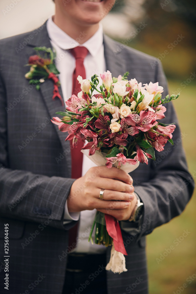 Stylish groom are holding bridal bouquet. Wedding bouquet in man hands