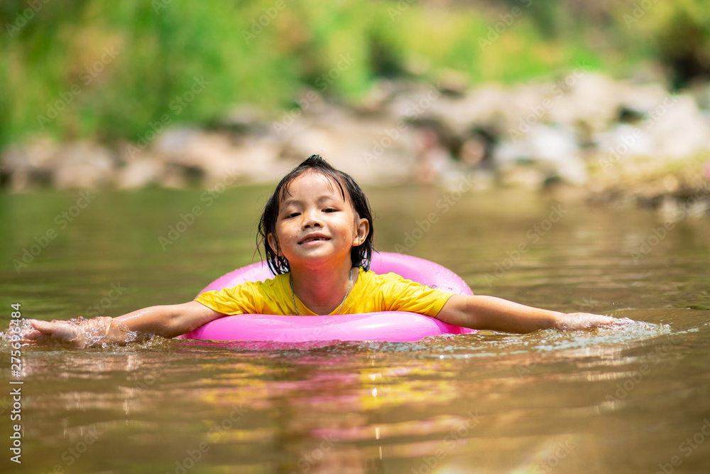 Fototapeta premium Little girl in pink pool ring swimming in water
