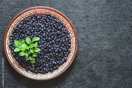 blueberries in a ceramic bowl top view. background with blueberries and a sprig of blueberry Bush and copy space. blueberries flat lay.