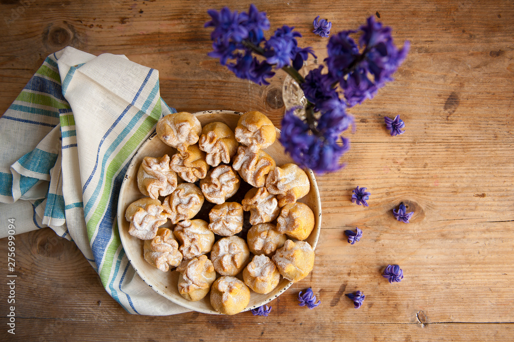 Fototapeta premium Homemade biscuit with violet hyacinth, white flower and yellow taraxacum on the wooden table