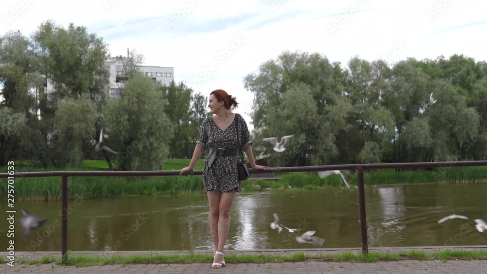 Tourist redhead woman enjoying day with birds flying in the background - Caucasian white girl wearing a dotted summer dress Tourist redhead woman enjoying day with birds flying in the background - Caucasian white girl wearing a dotted summer dress