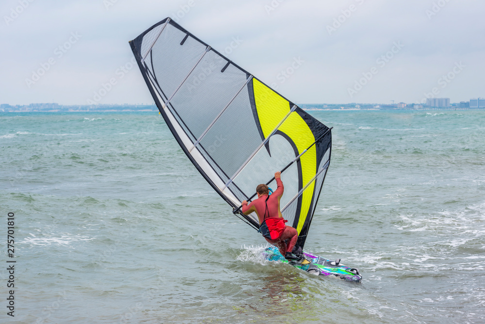 Foto Stock the fat man windsurfer in the red wetsuit with a board very cool  rides in windsurf with yellow sail | Adobe Stock