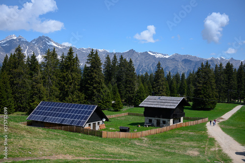 sustainable photovoltaics houses in mountain alps at forest with blue sky