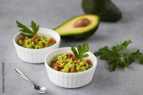 Appetizer of avocado in white bowls over gray background. Guacamole.