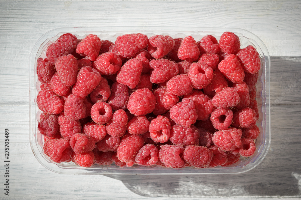 Red raspberry in container on white wooden table, top view Red raspberry in container on white wooden table, top view