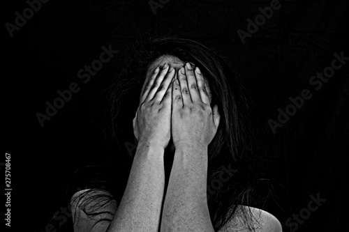 Stopping violence against women, Woman covering her face in fear of domestic violence, Dark tone