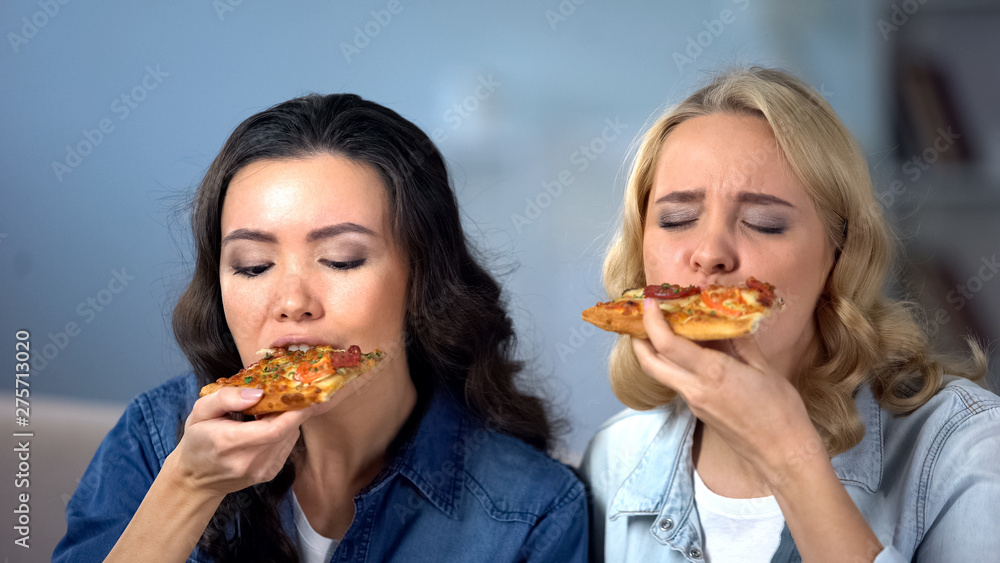 Hungry female friends enjoying delicious pizza, Italian cuisine, food delivery