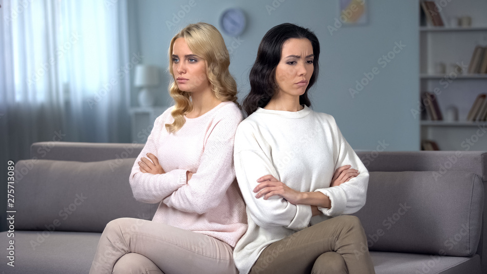 Two angry women being in quarrel sitting on sofa, conflict between friends Two angry women being in quarrel sitting on sofa, conflict between friends
