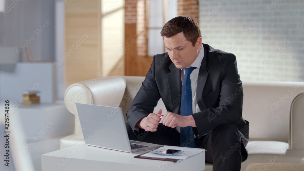 Young businessman working on laptop in apartment, managing company remotely Young businessman working on laptop in apartment, managing company remotely