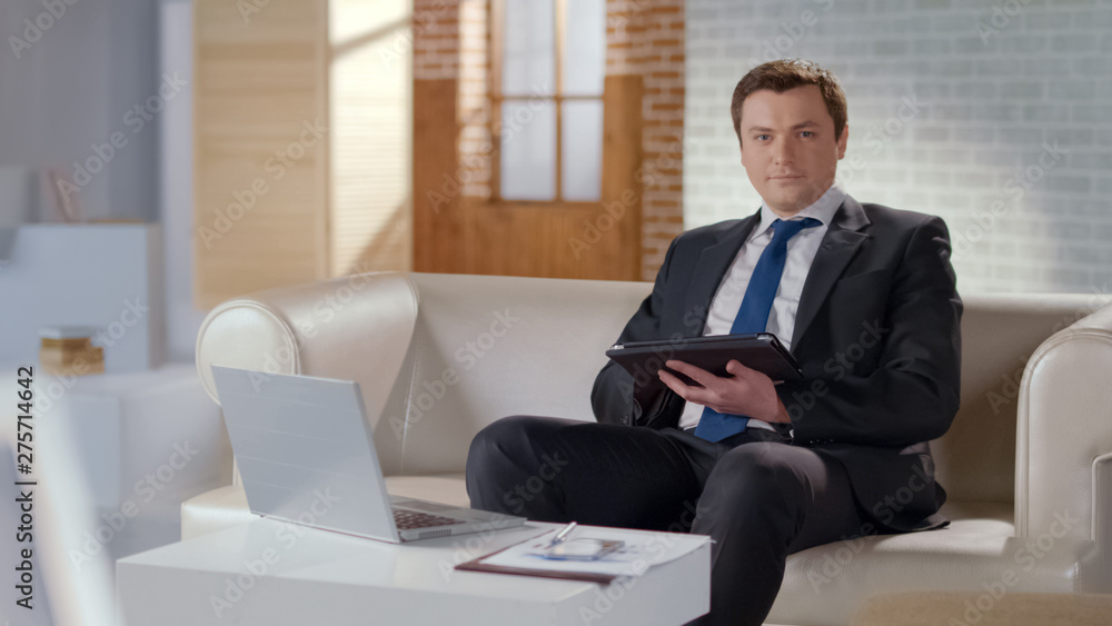 Young man in suit using tablet in office, modern technologies to manage business Young man in suit using tablet in office, modern technologies to manage business