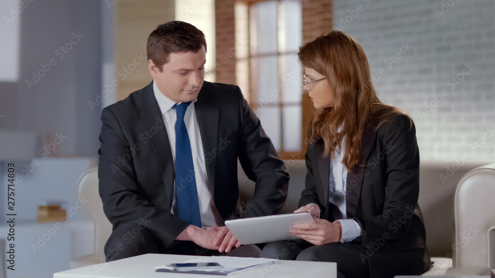 Female employee showing company reports on digital tablet, presentation to boss Female employee showing company reports on digital tablet, presentation to boss