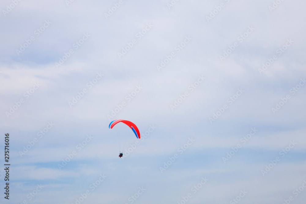 People gliding using a parachute on the background of the blue sky People gliding using a parachute on the background of the blue sky