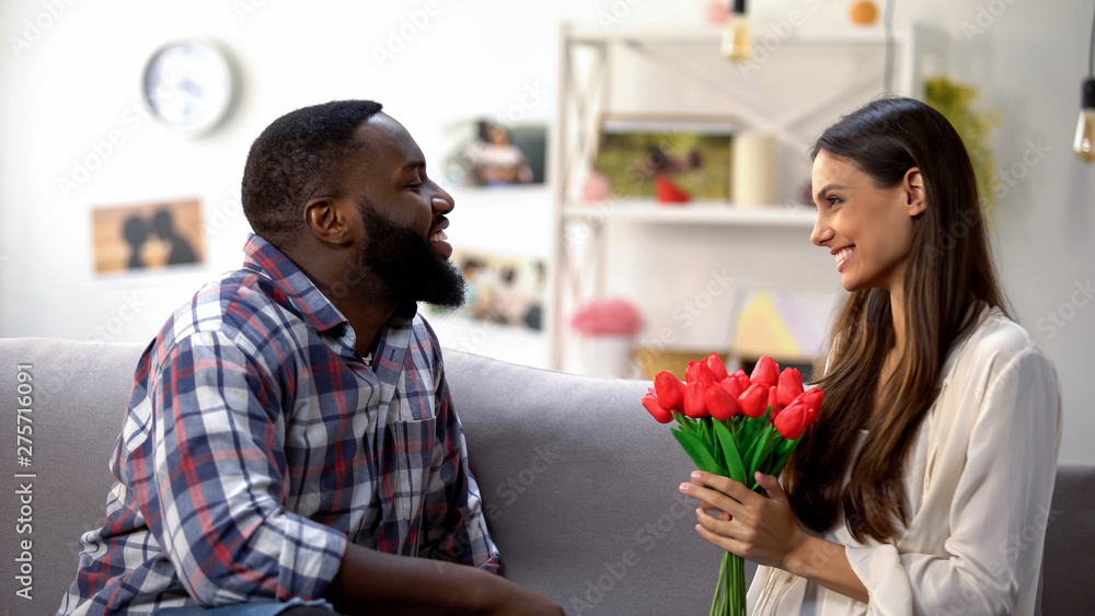 Caucasian girl holding tulips, present from afro-american male, anniversary gift Caucasian girl holding tulips, present from afro-american male, anniversary gift