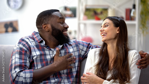 Laughing mixed-race couple joking, having funny conversation, togetherness