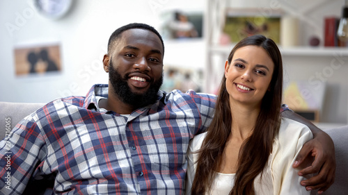 Sweet mixed-race couple hugging and looking at camera, spending time together